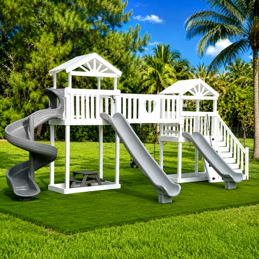 Children's vinyl playground with white play structure and gray slides on a grassy area with trees in the background.